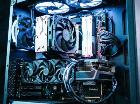 A fully built gaming PC with side panel removed showing GPU, CPU cooler, RAM, and NVMe storage lit with blue and white directional lighting against a black background